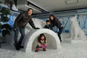 A family posing in front of an igloo in Snow City